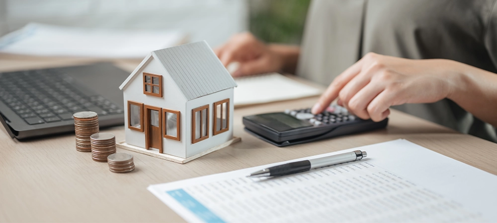 residential, financial, loan, rental, finance, agreement, estate, property, real, insurance A woman is sitting with a calculator and a house model