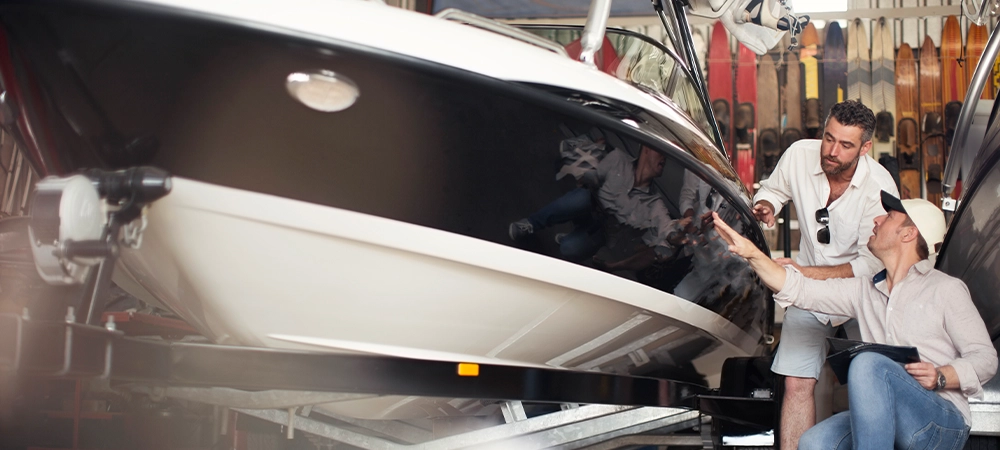 Two men inspecting a boat in a workshop.