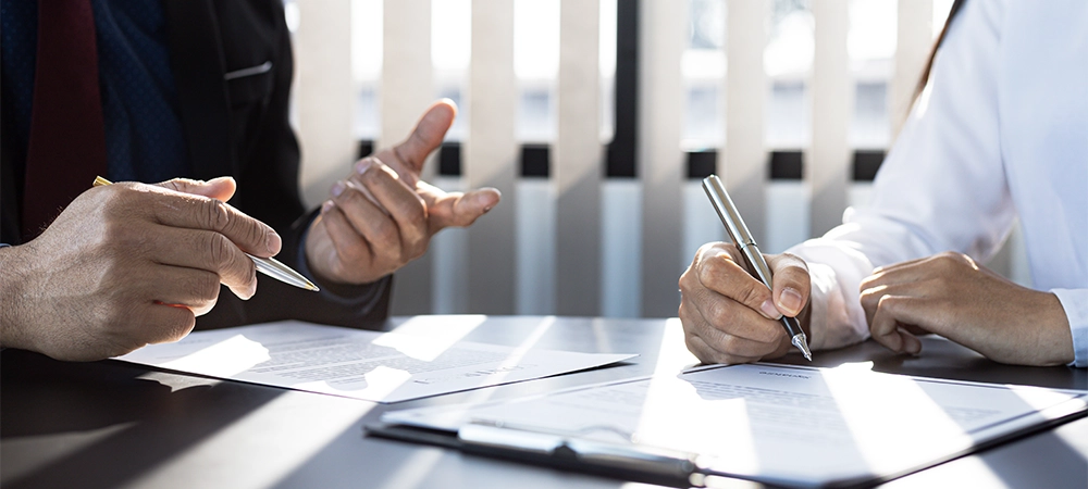 The home insurance salesman and the customer are signing an insurance agreement with their insurance company, accepting the terms and benefits. Home and real estate insurance concept.